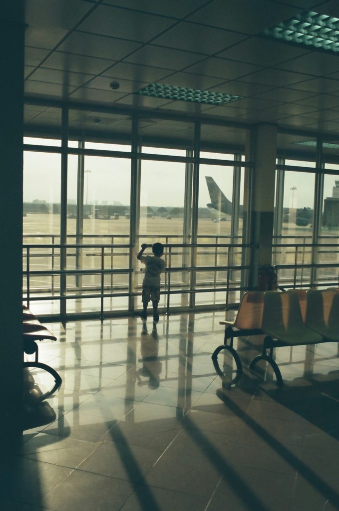 boy staring out the windows of an airport terminal